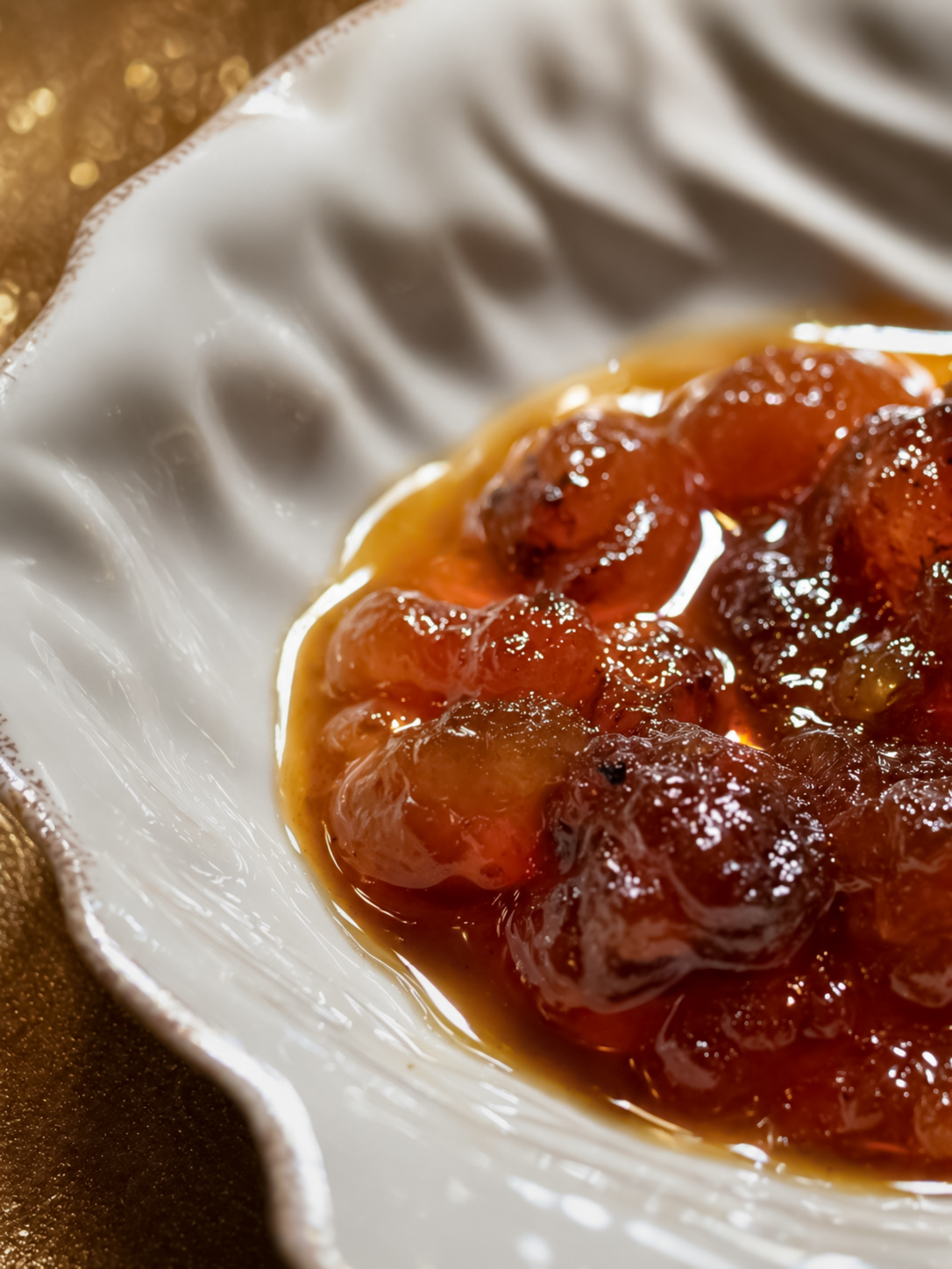 A close-up of glazed grape-form dessert in a fluted ceramic dish
