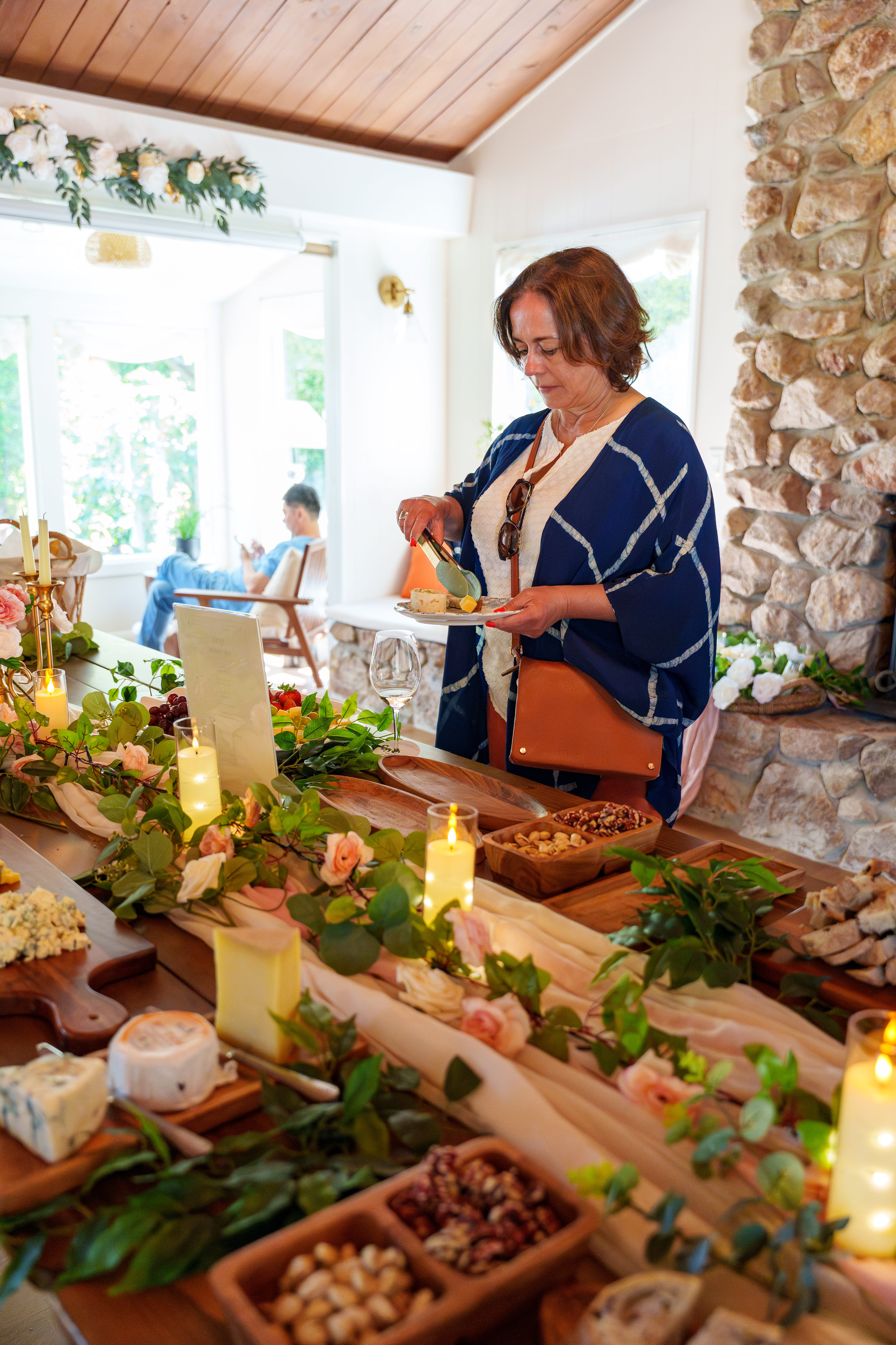 A guest in a blue patterned wrap selecting bites from the cheese and herb spread