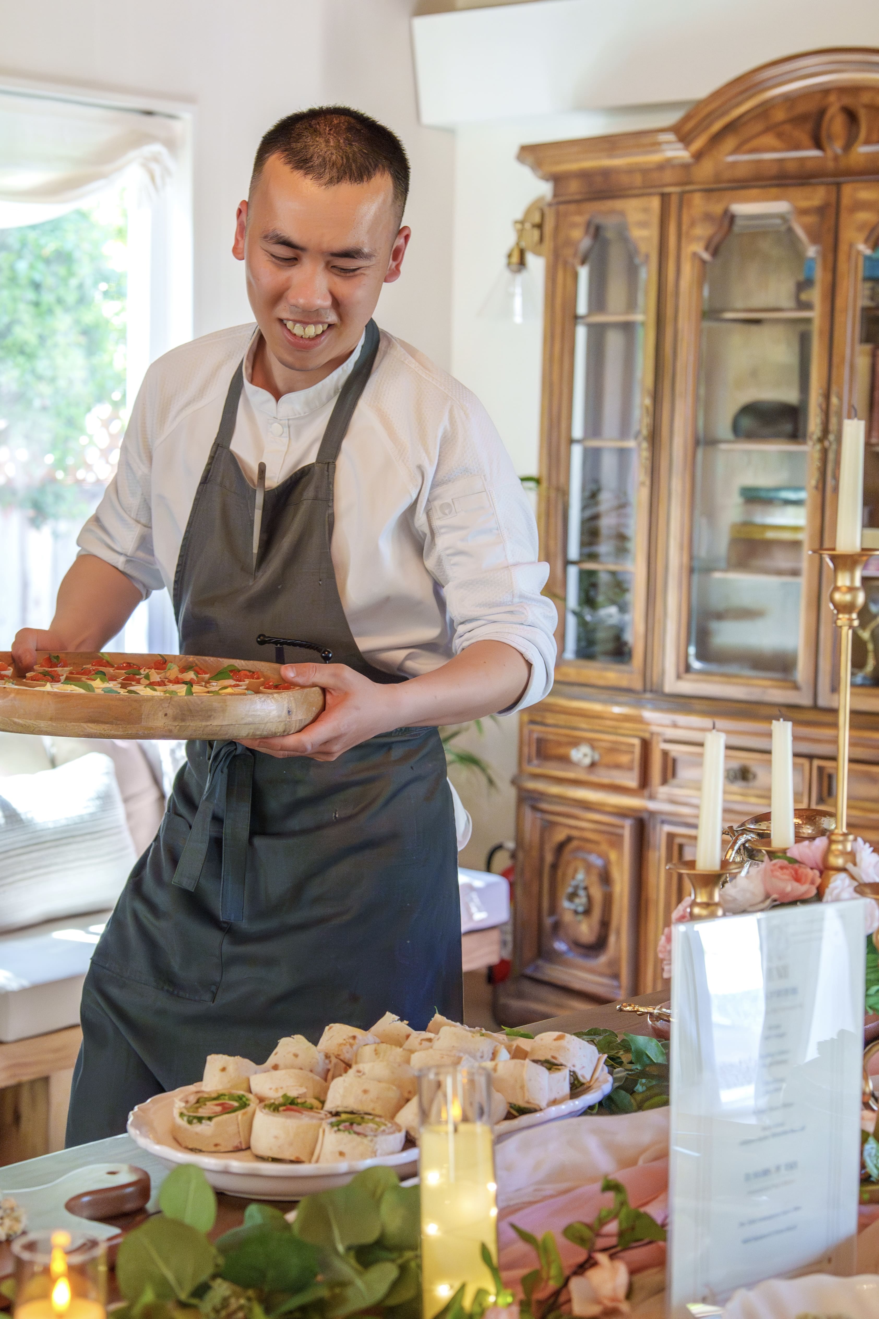 Chef Desmond Ho carrying a wooden board of fresh canapés to the table