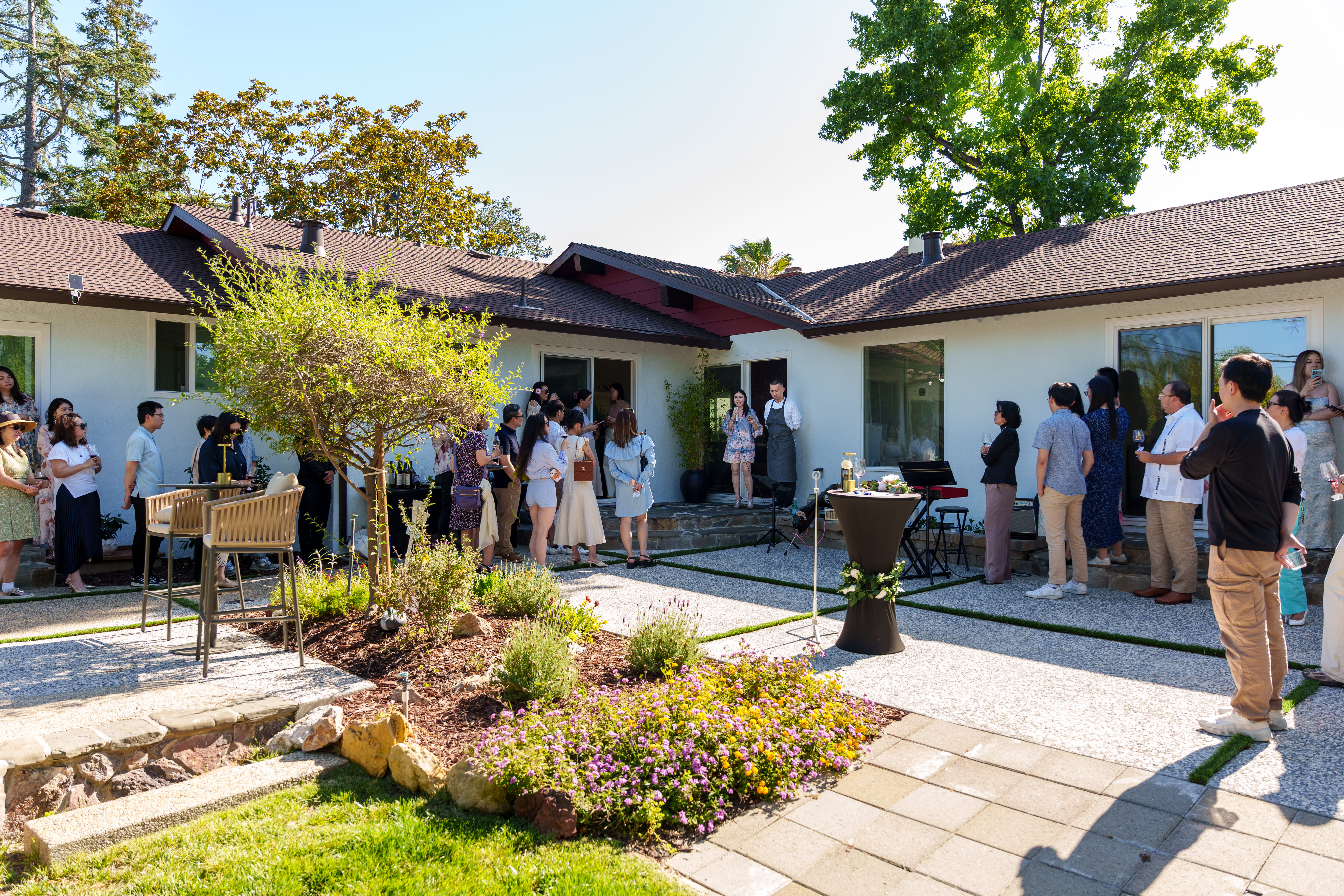 Members gathered in conversation across the winery courtyard on a sunlit afternoon