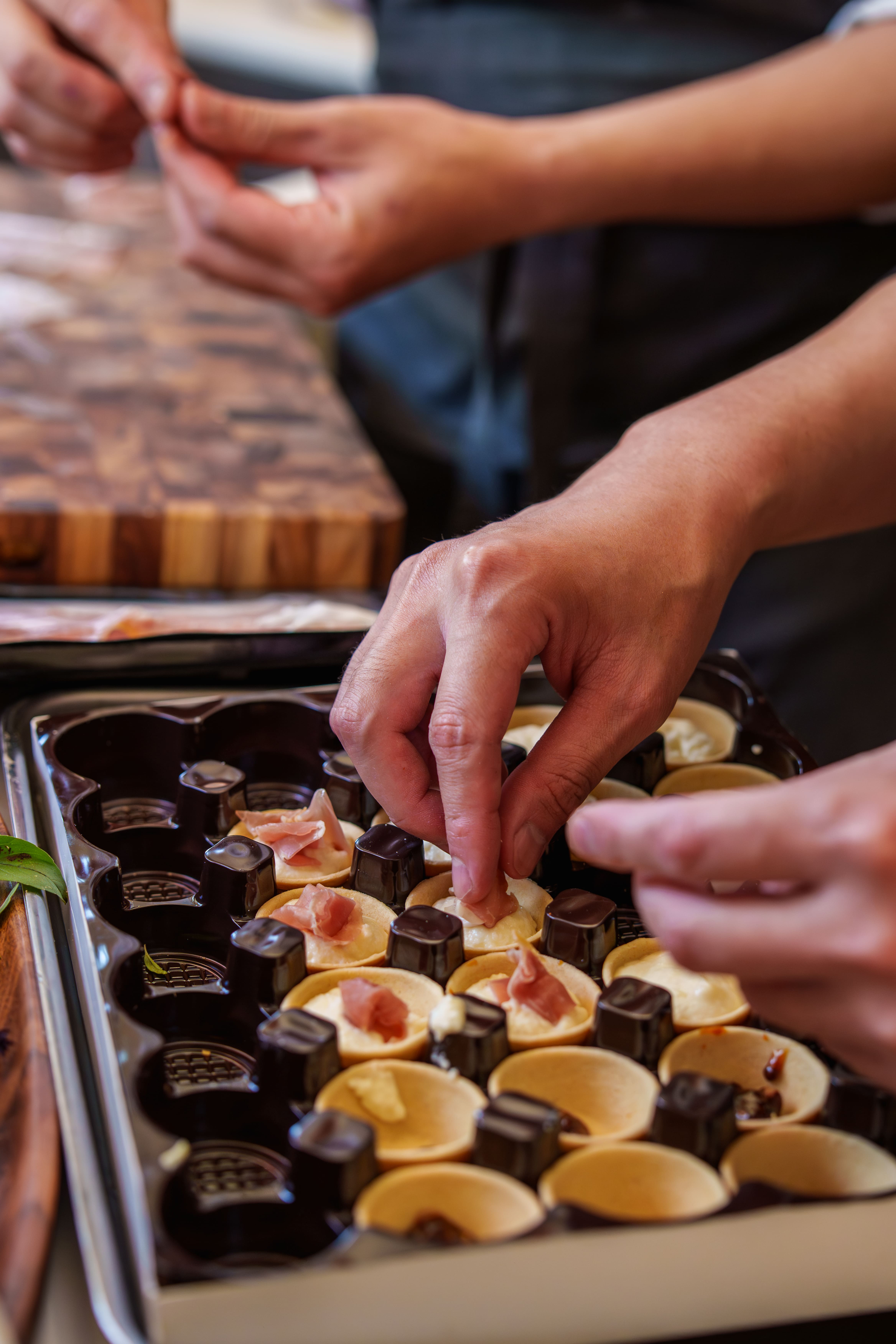 A close-up of Chef Desmond's hands plating delicate canapés in the back kitchen