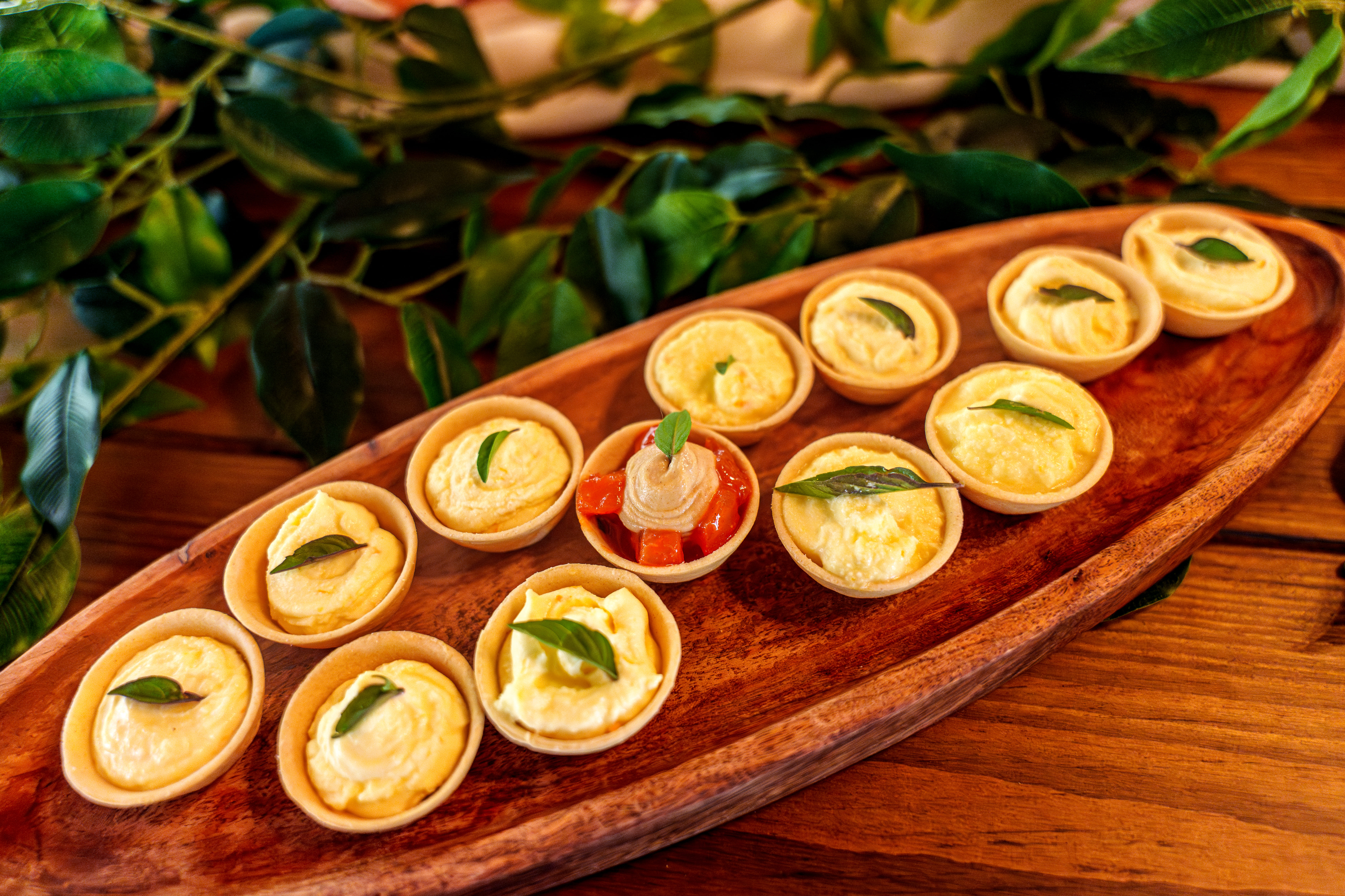 An assortment of small canapés arranged on a wooden plate with herbs